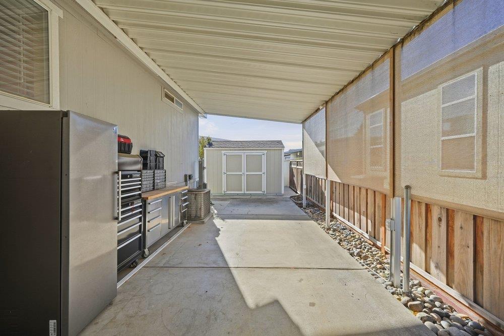 Covered outdoor work area with tool cabinets, a concrete walkway, and a small shed.