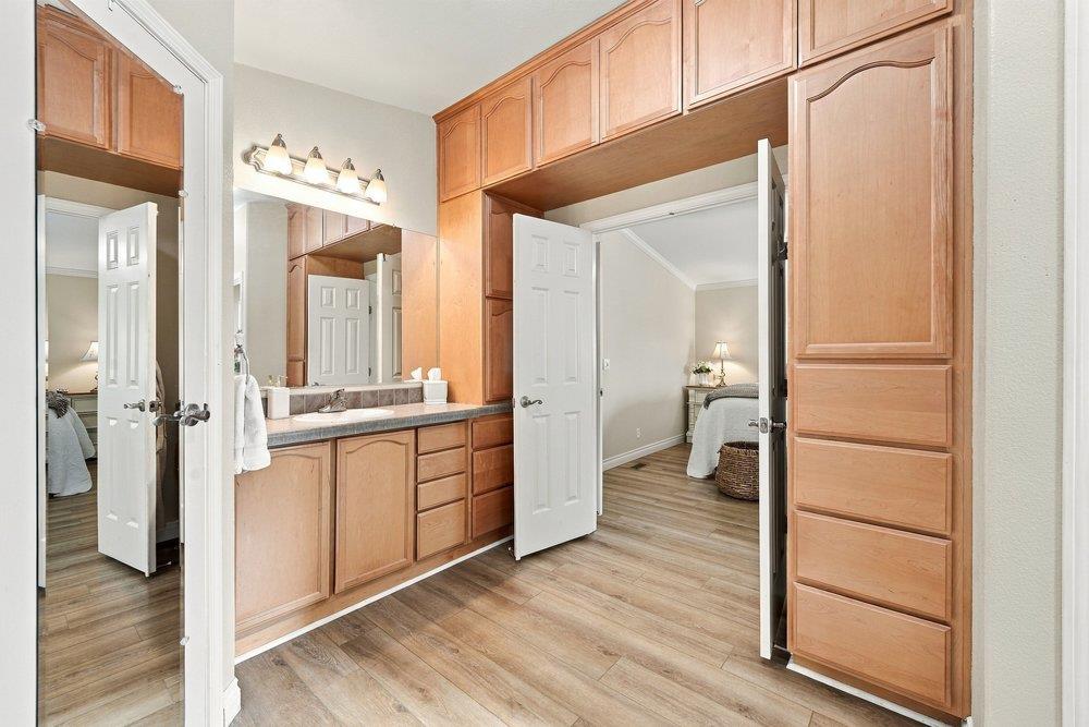 Bathroom vanity with extensive wood cabinetry, a large mirror, and an open doorway to the bedroom.