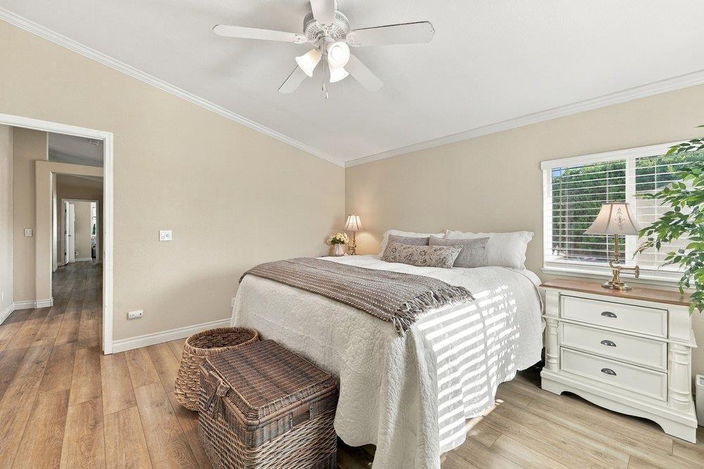 Bedroom with a white bed, wicker trunk, and dresser beneath a sunlit window.