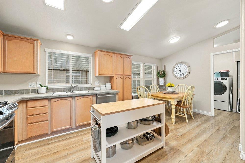 Kitchen and dining area with wood cabinets, a central island, and a laundry area through the doorway.