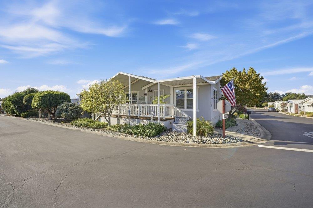 Manufactured home on a landscaped corner lot, with a covered porch and an American flag.