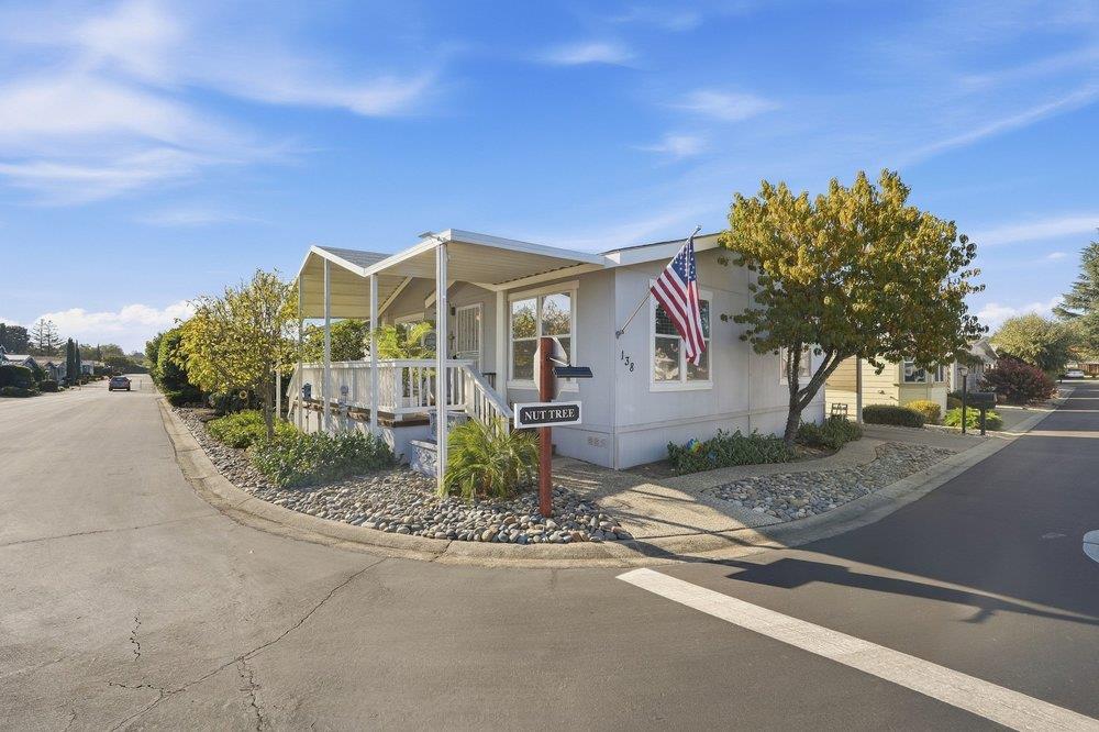 Home with a covered porch, American flag, and landscaped rock garden at the street corner.