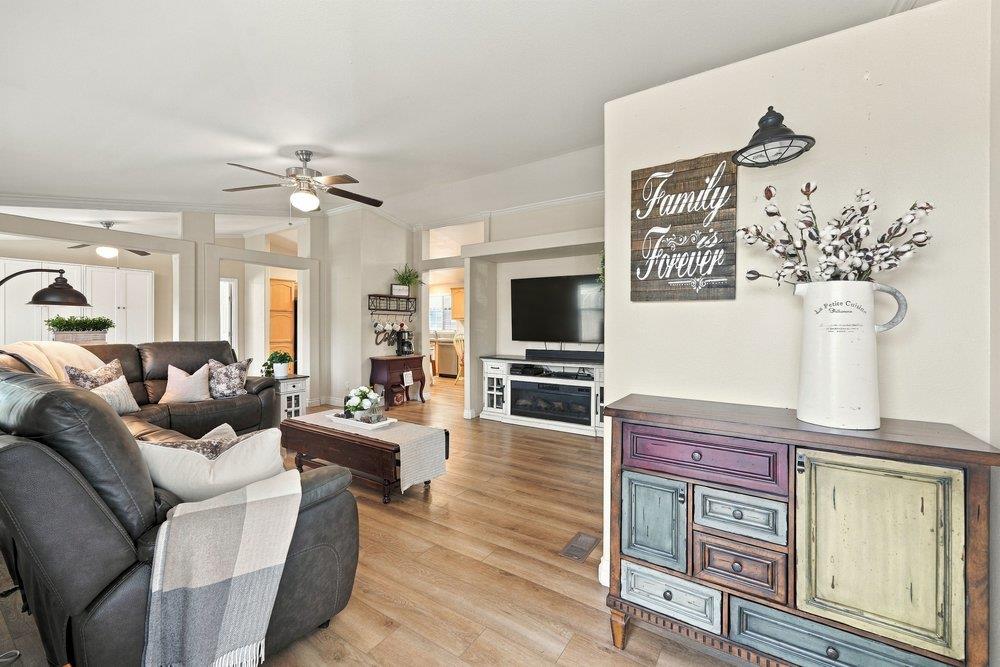 Living room with leather sectional, wall-mounted TV, wood floors, and a distressed console in the foreground.