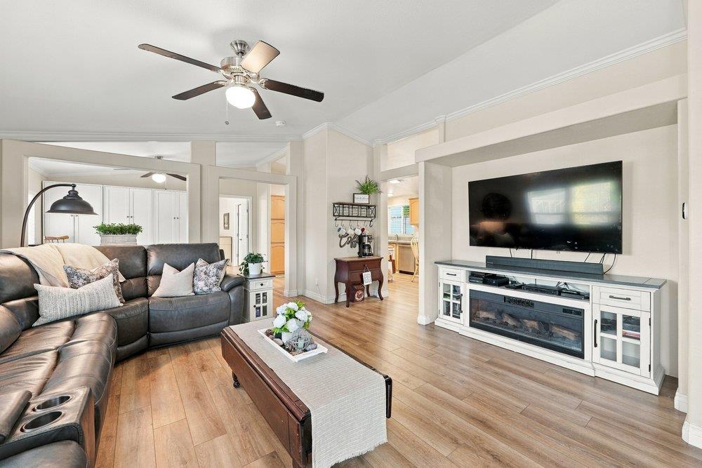 Living room with a leather sectional, wood floors, and a television above a fireplace.