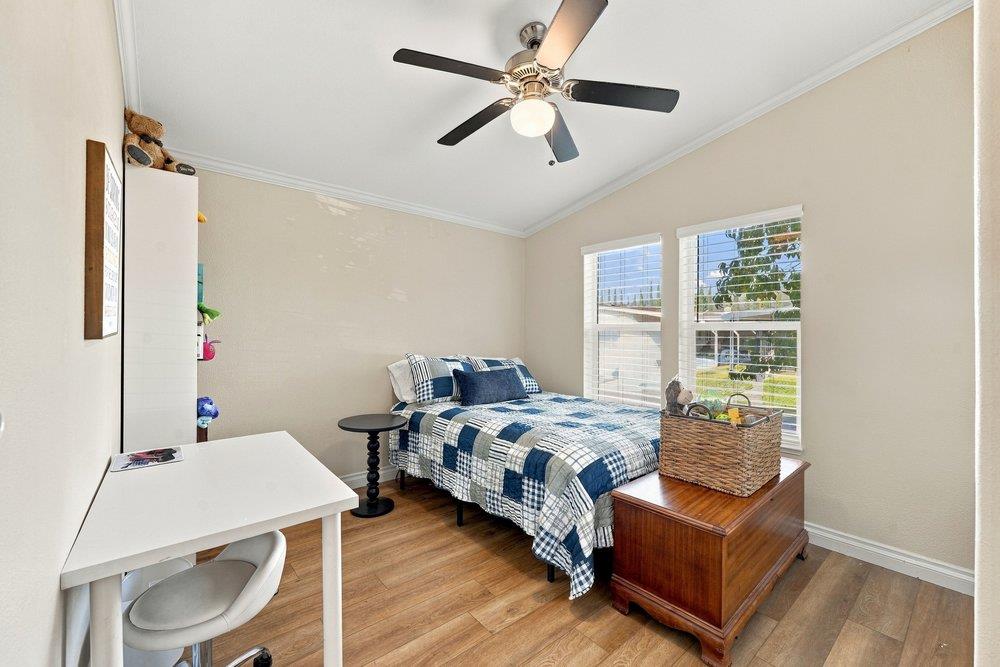 Bedroom with blue-and-white patchwork bedding, a white desk, and two bright windows.