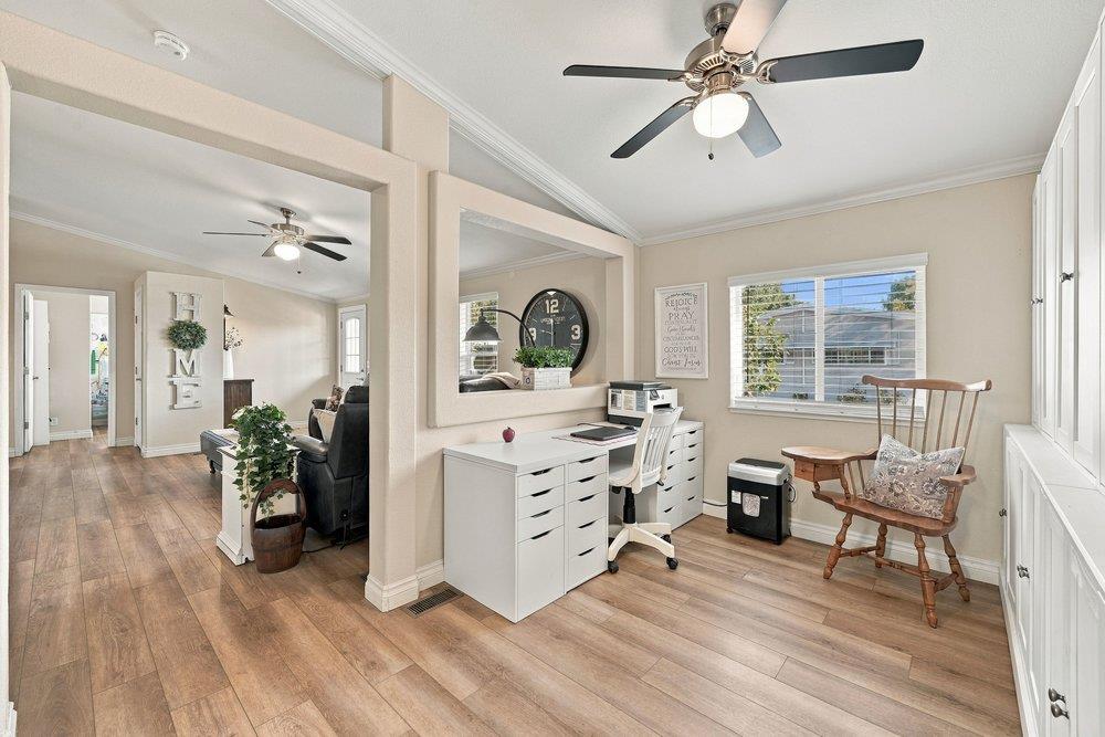 Home office with white desks, a ceiling fan, and a wooden rocking chair by the window.