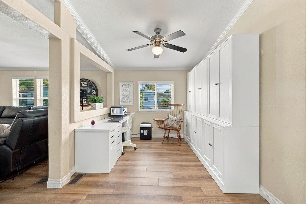 Home office with white built-in cabinets, a desk, and a wooden chair by the window.
