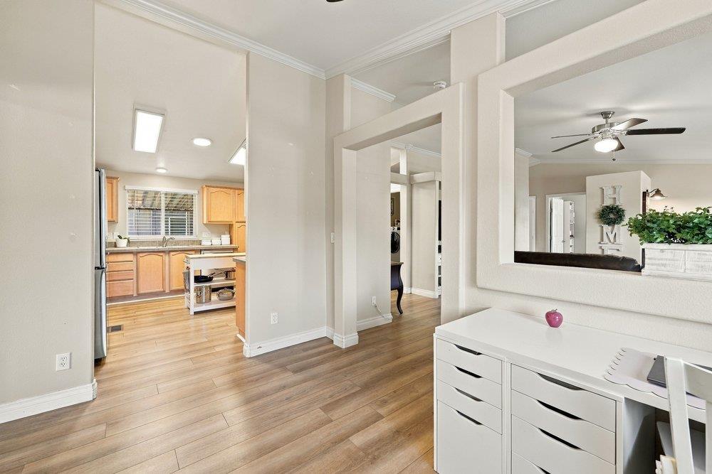 Kitchen opening onto a wood-floored room with a white desk and large mirror reflecting the living area.