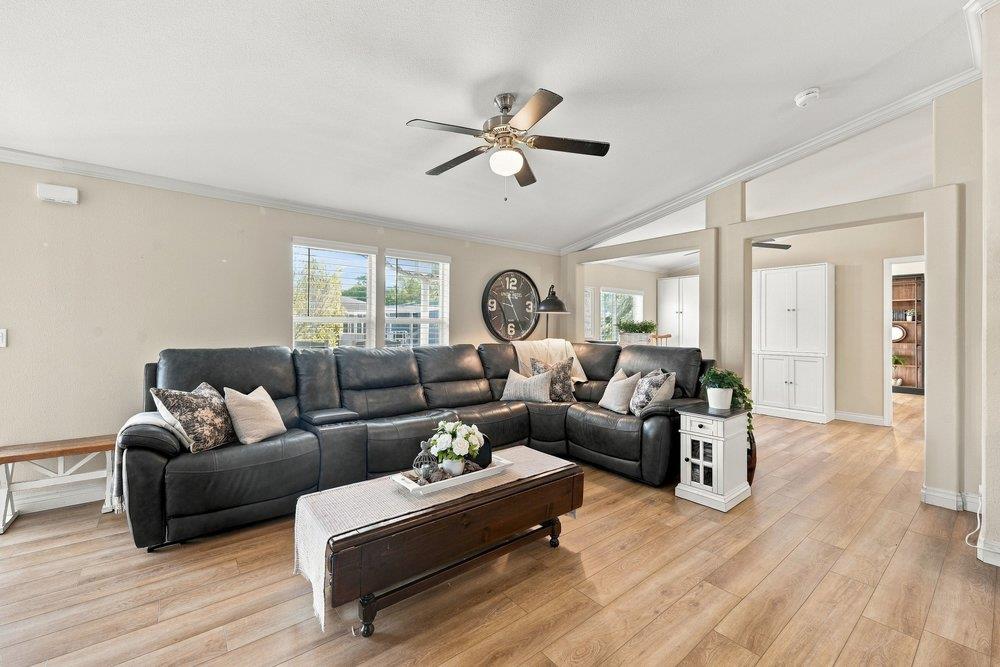 Living room with a black leather sectional, wood flooring, and an open doorway to an adjoining room.