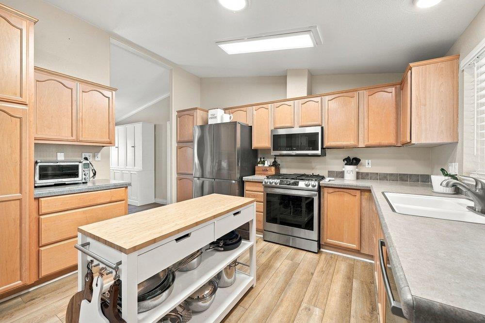 Kitchen with honey-colored cabinets, stainless steel appliances, and a butcher-block island.