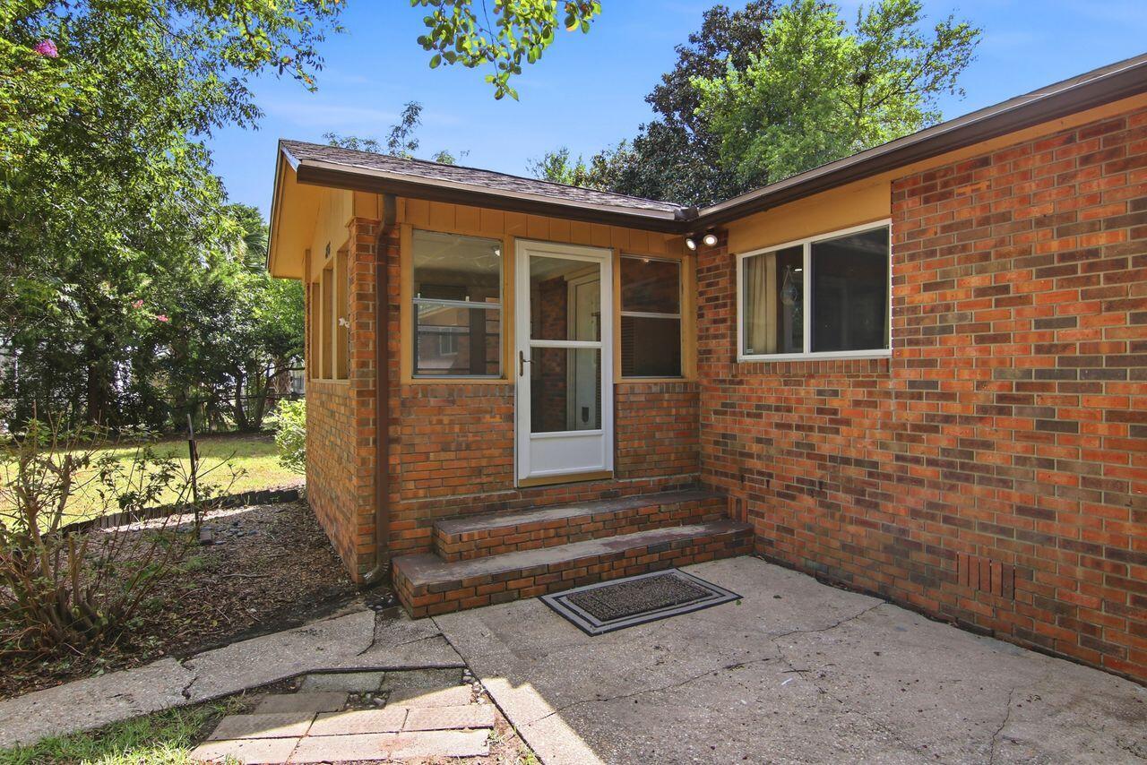Red brick house with a white entry door, brick steps, and a concrete patio.