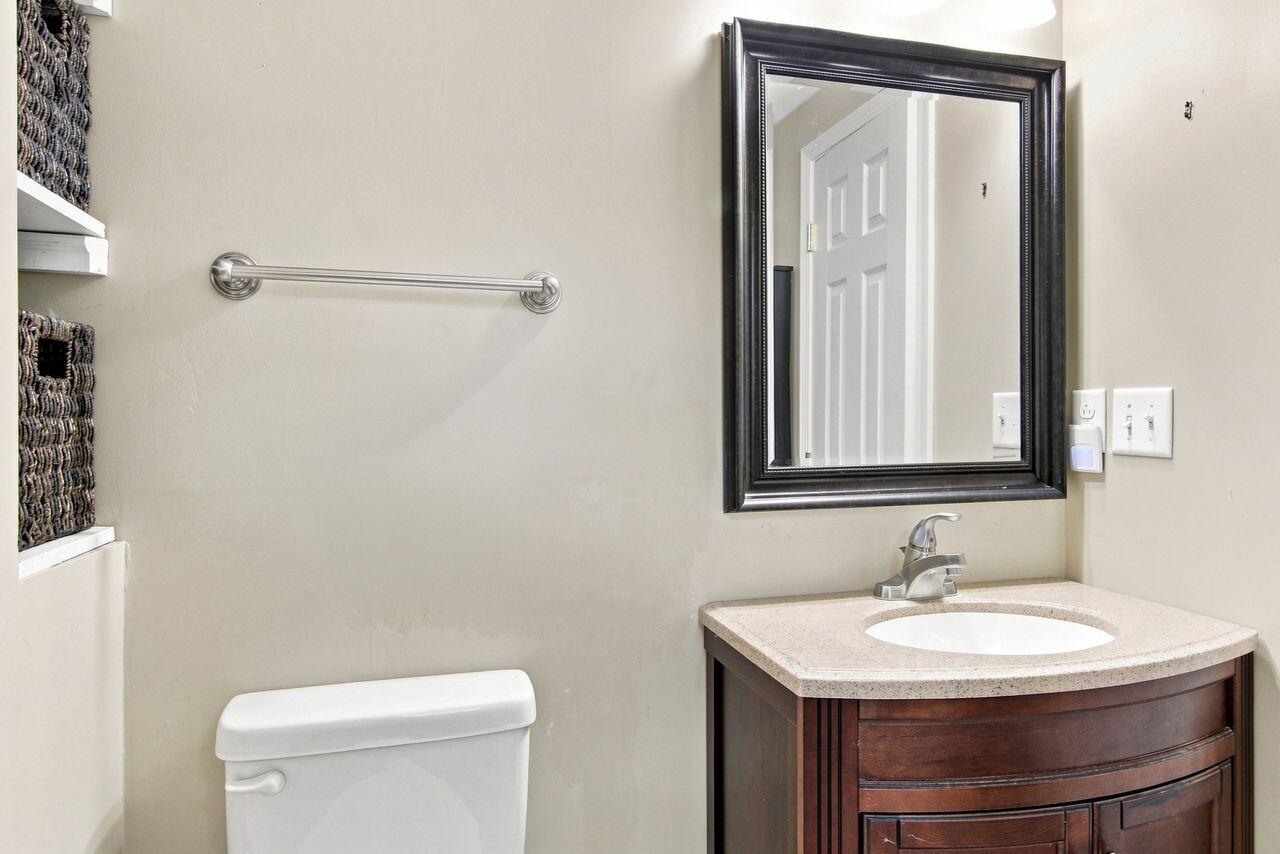 Bathroom vanity with a white sink, dark wood cabinetry, and large framed mirror.