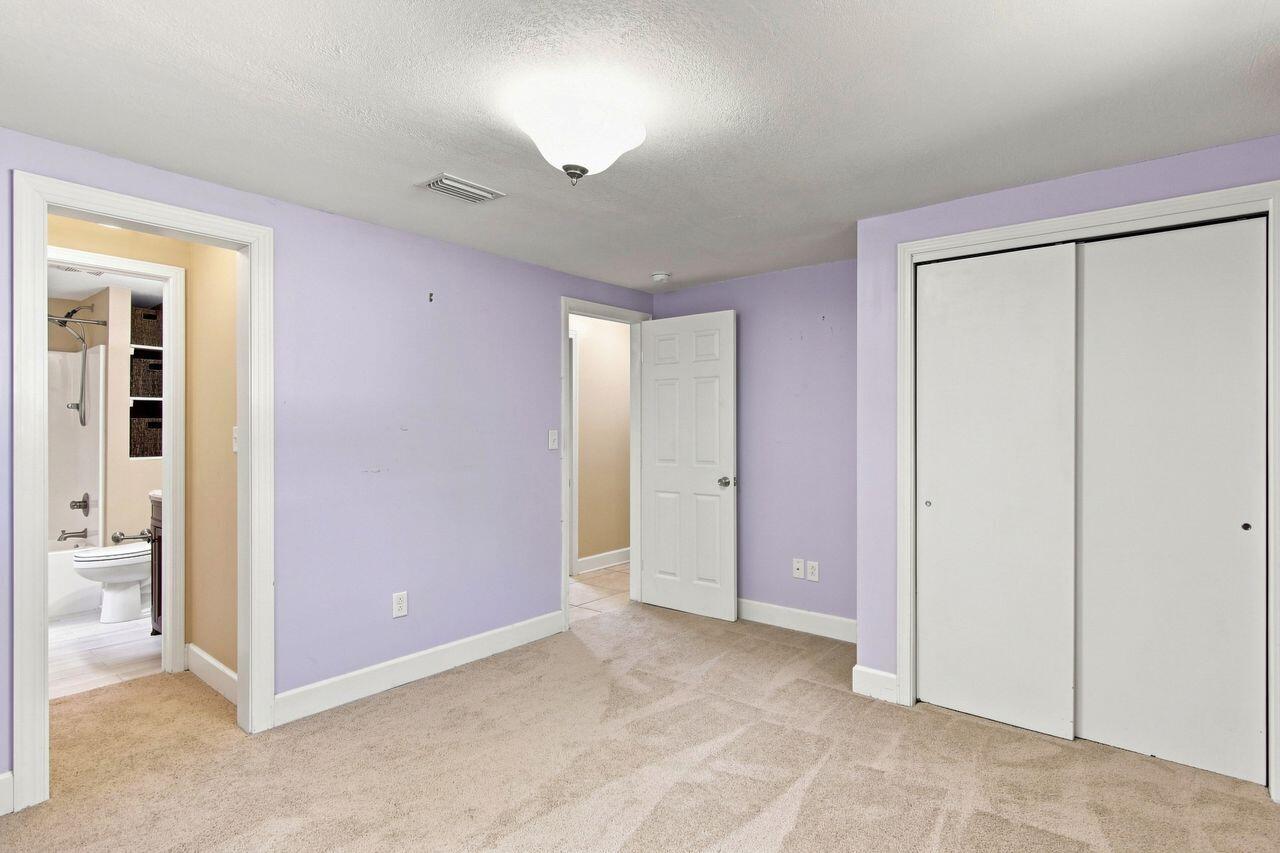 Empty bedroom with lavender walls, beige carpet, and a large white sliding-door closet.