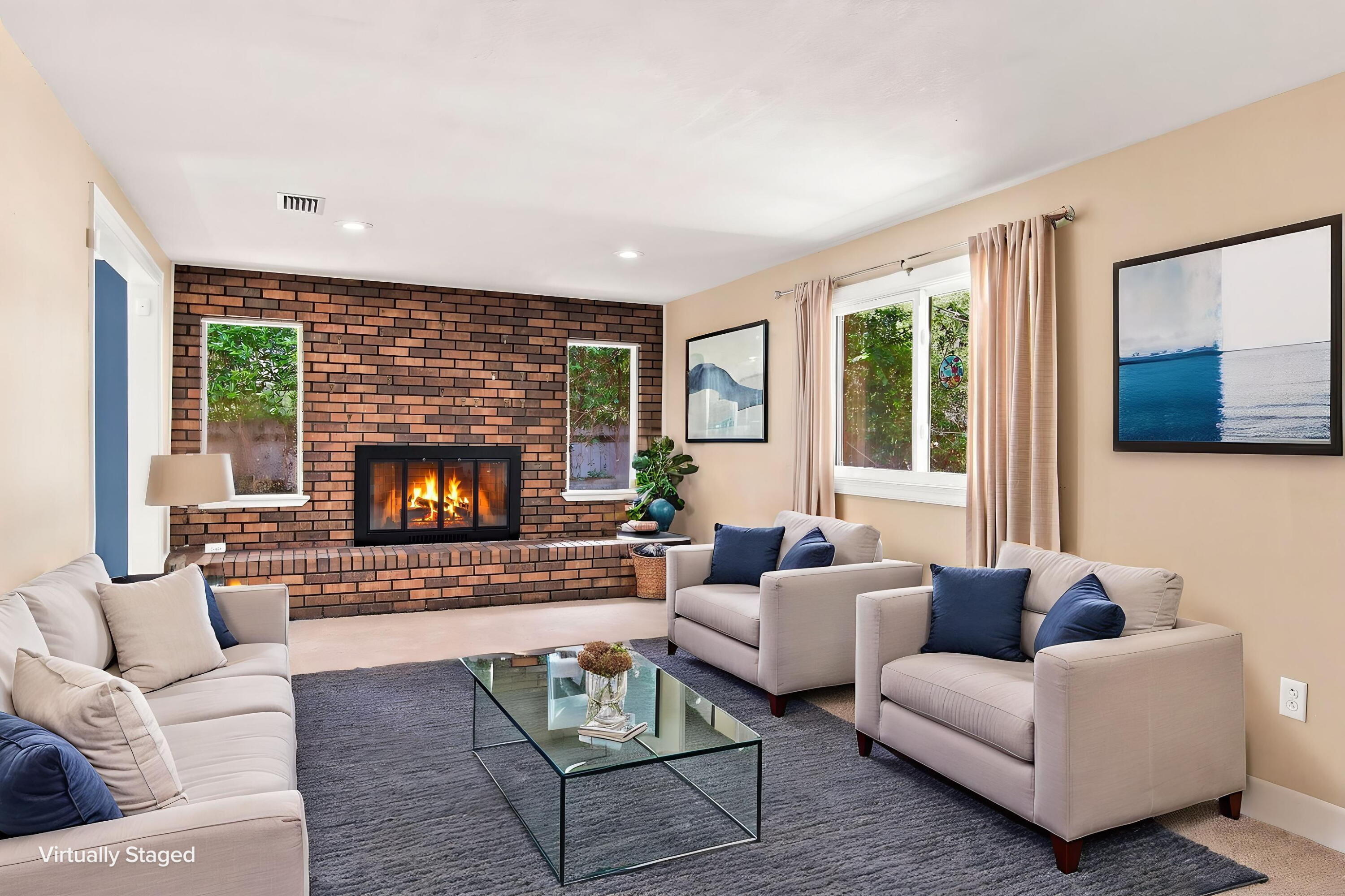 Virtually staged living room with a brick fireplace, cream sofas, and a glass coffee table.