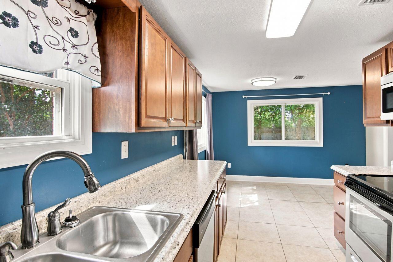 Kitchen with blue walls, wood cabinets, a speckled countertop, and a stainless-steel sink.