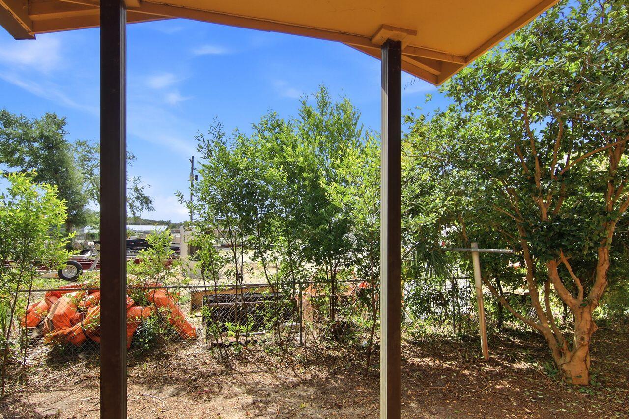 Covered patio overlooking a tree-filled yard and chain-link fence.