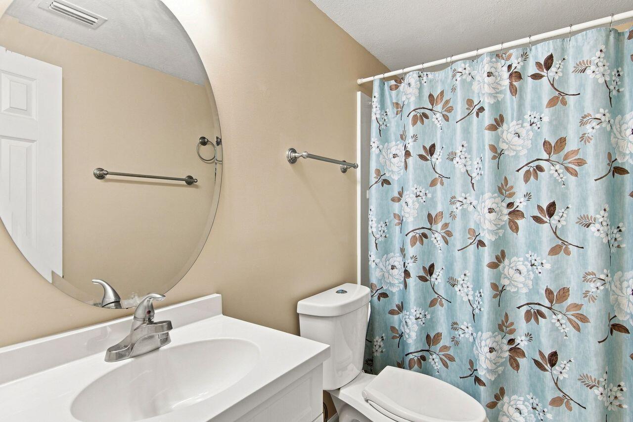 Bathroom with a large oval mirror and blue floral shower curtain.