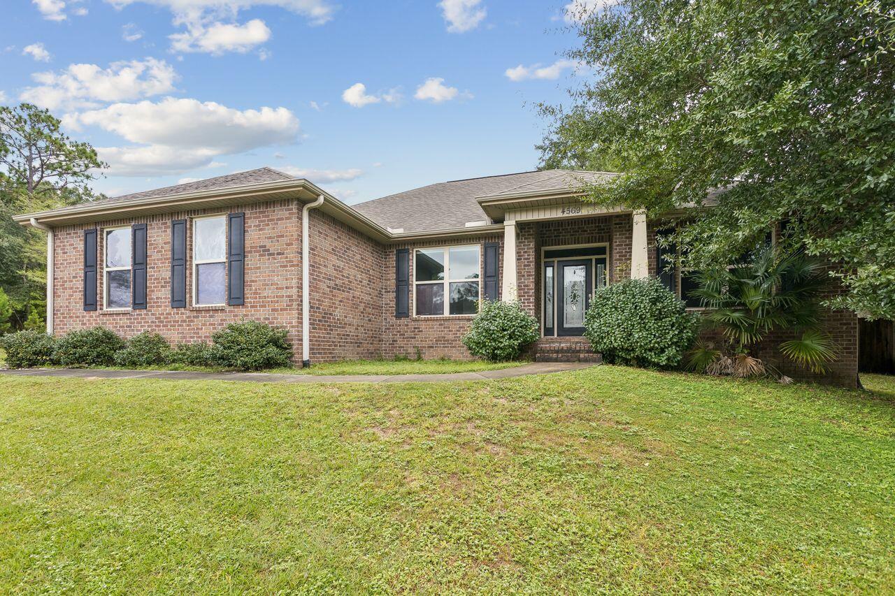 Single-story brick house with dark shutters, a recessed front entrance, and a broad lawn.