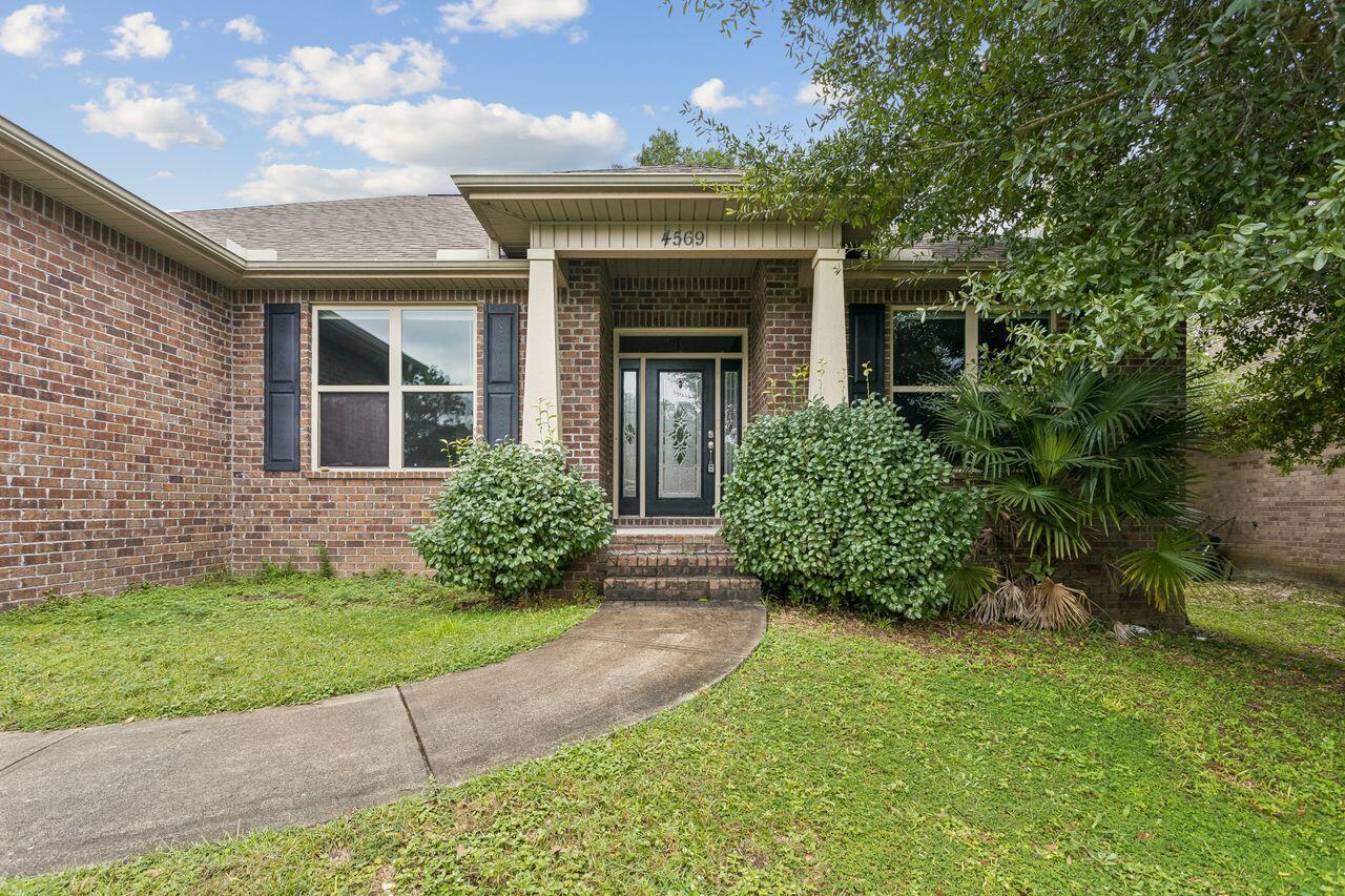 Brick home with a covered entry and curved walkway leading to the front door.