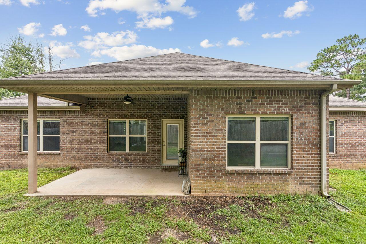 Brick house rear with a broad covered patio and concrete slab.