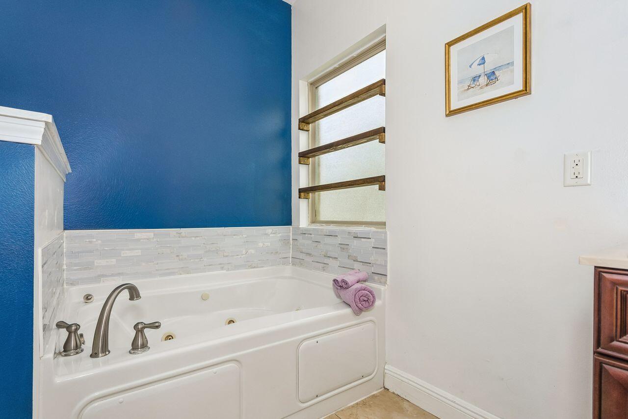 Bathroom jetted tub with chrome fixtures, blue accent wall, and mosaic tile backsplash.