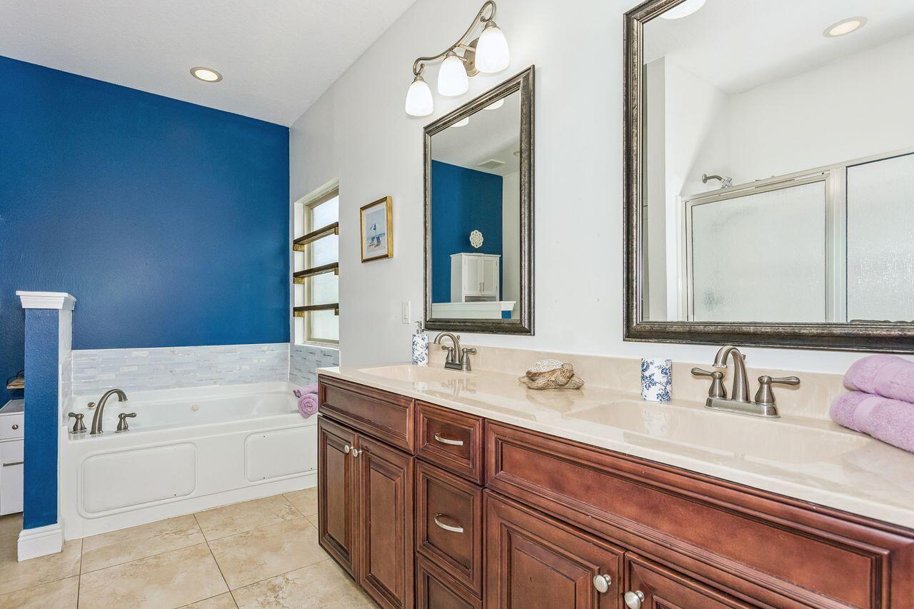 Bathroom with a built-in soaking tub, blue accent wall, and long dark wood double vanity.