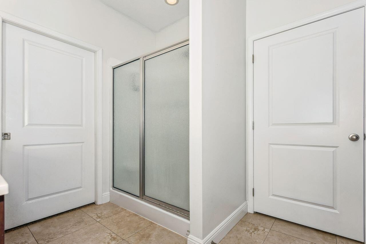 Bathroom with a frosted-glass shower enclosure and beige tiled floor.