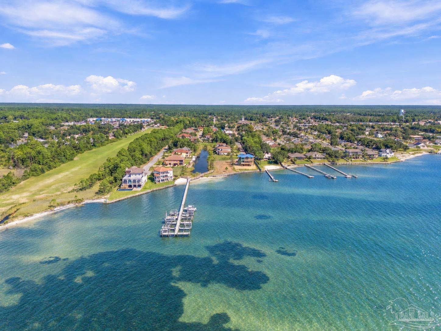 Aerial view of waterfront homes and docks along clear blue-green water.