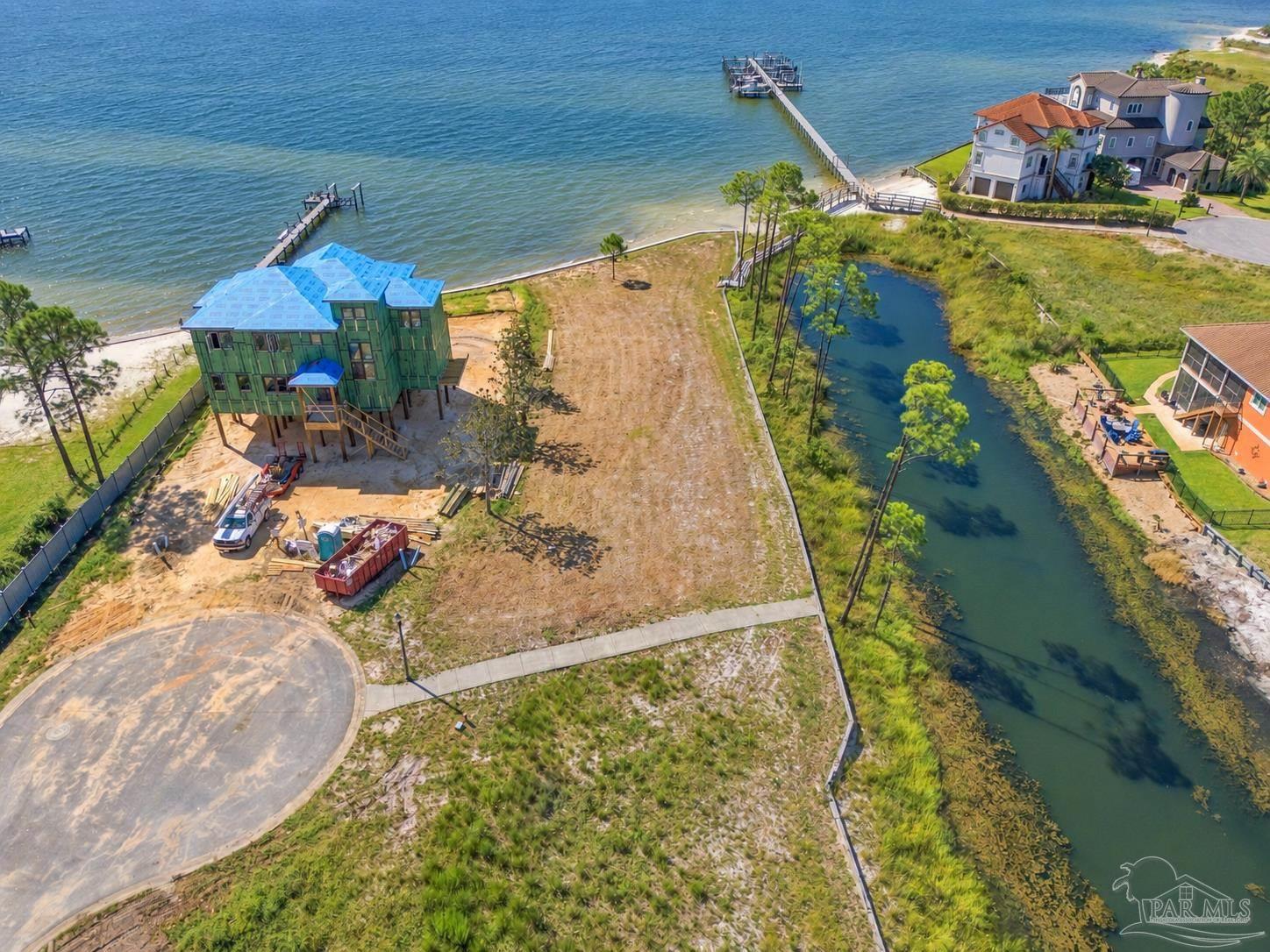 Waterfront lot with a house under construction beside a broad waterway and marshy channel.