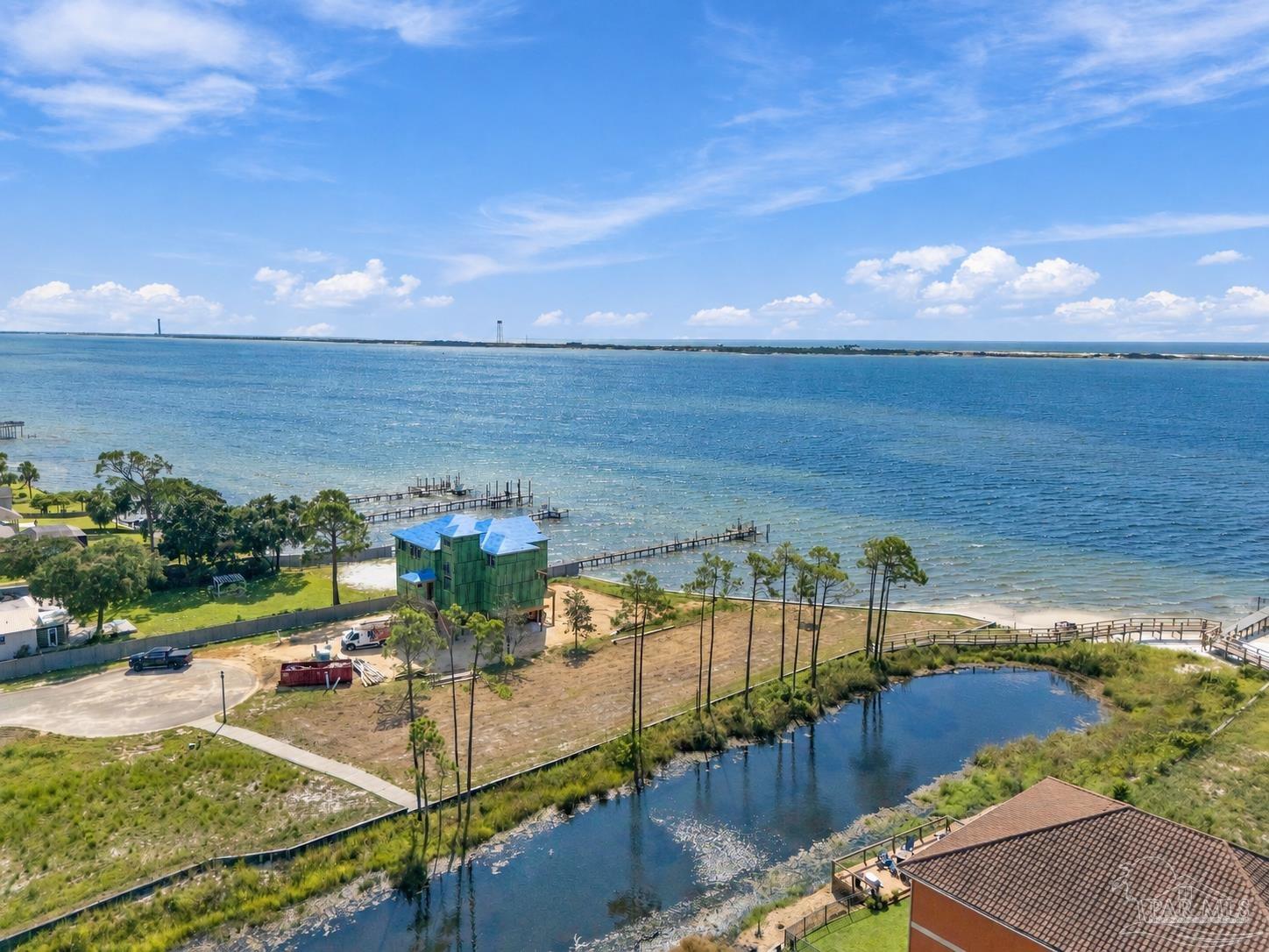 Aerial waterfront view with docks and a building under construction along the shore.