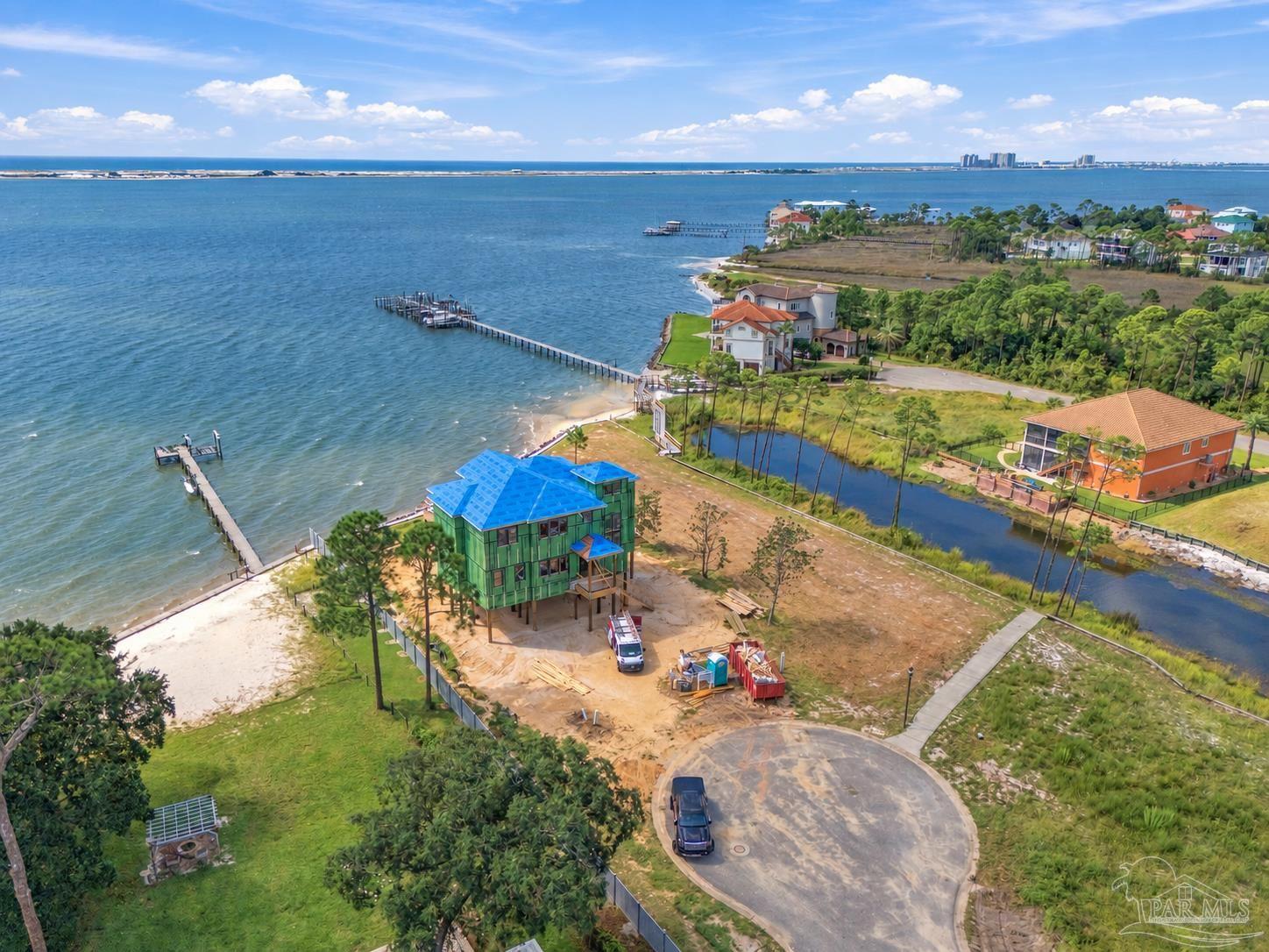 Waterfront home under construction with a bright blue roof, private docks, and bay views.