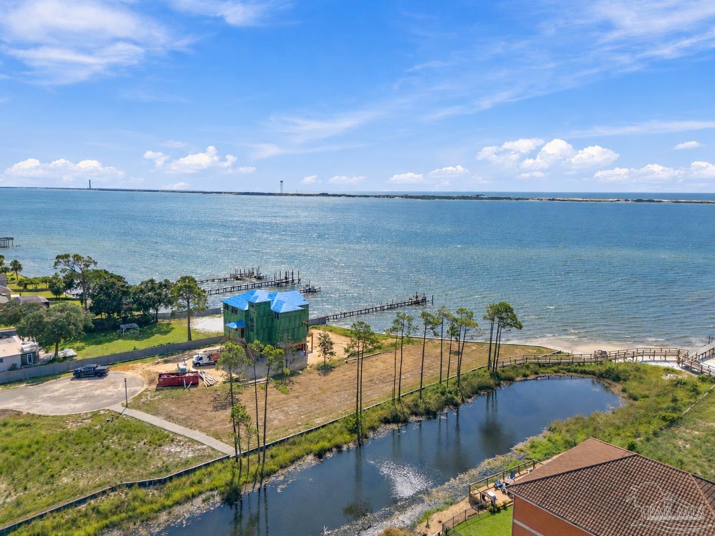 Aerial view across a bay toward the distant shoreline, with waterfront homes and docks below.
