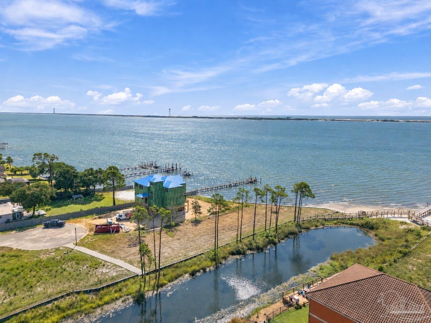 Aerial view of waterfront homes, docks, and a canal beside a broad expanse of water.