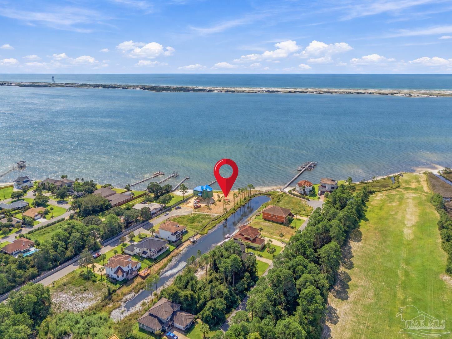 Aerial view of waterfront homes, canals, and shoreline with the listed lot marked in red.