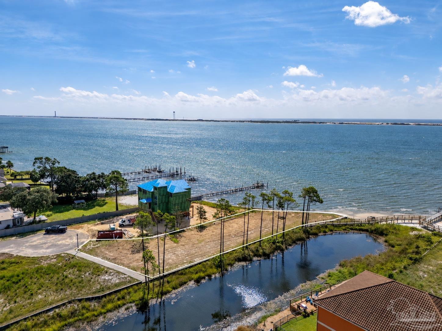 Aerial waterfront view with docks, a canal, and a cleared construction lot.