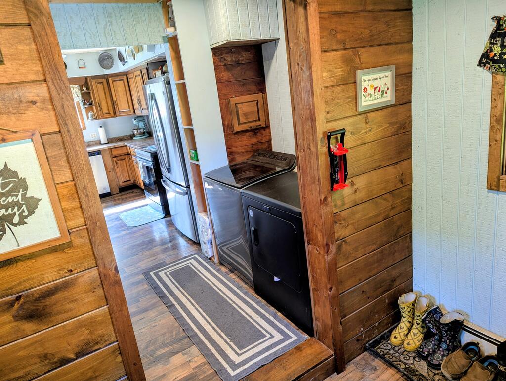 Laundry area with black washer and dryer beside a rustic kitchen and patterned runner.