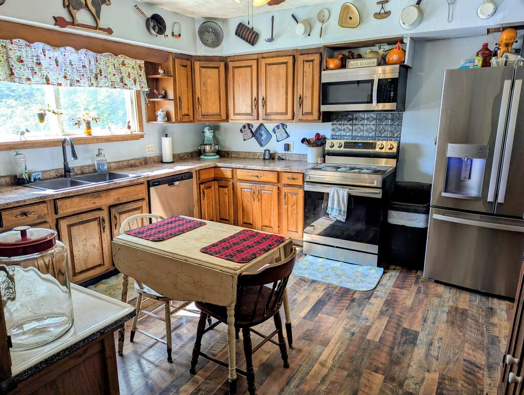 Kitchen with wooden cabinets, stainless steel appliances, and a small dining table by the window.