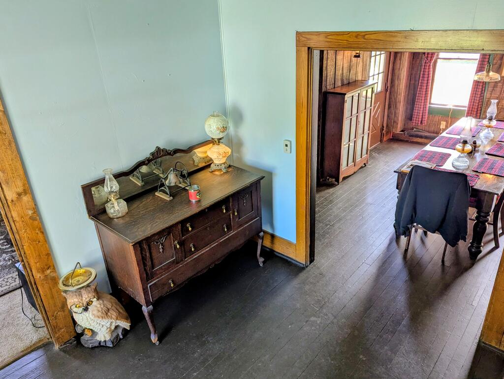 Antique sideboard beside a doorway to a wood-paneled dining room with a long table.