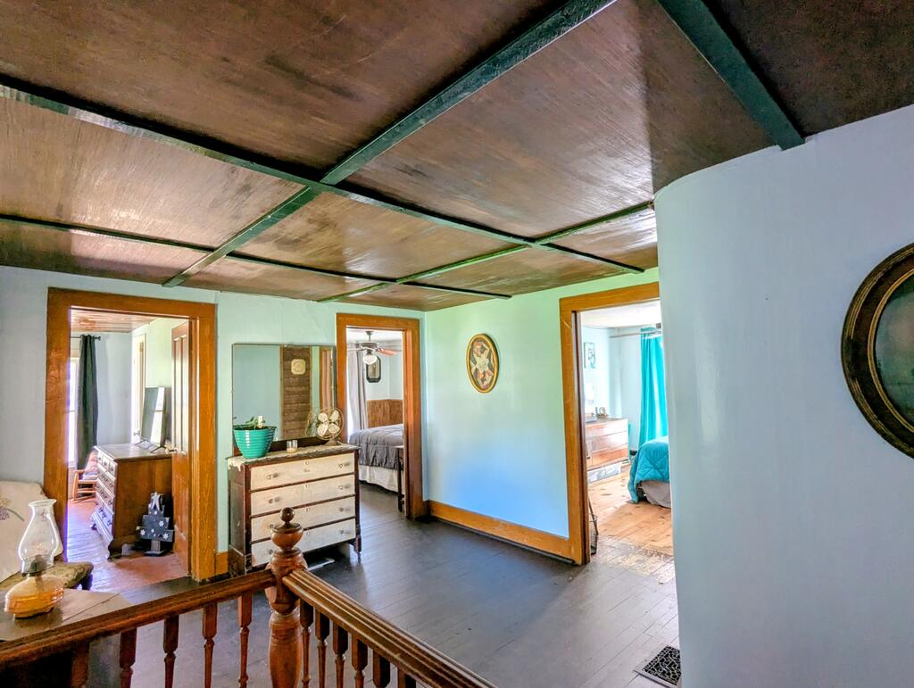 Upstairs hallway with a paneled wood ceiling, dark floors, and open bedroom doorways.