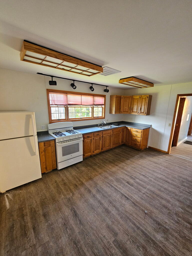 Kitchen with wood cabinets, gray countertops, a gas range, and a wide window.