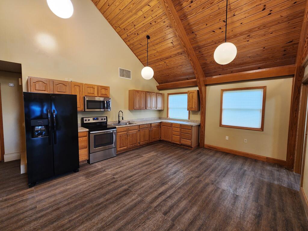 Kitchen with wood cabinetry, stainless steel appliances, and a vaulted wood ceiling.