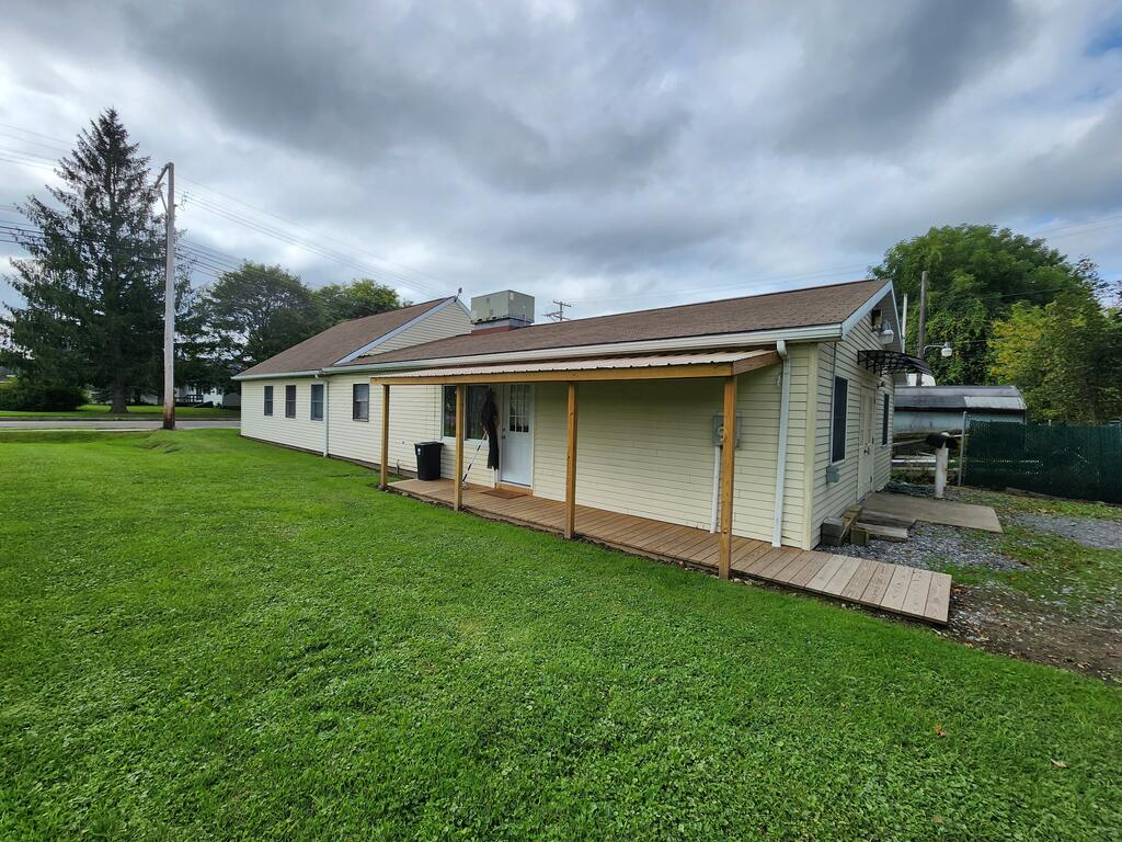 Single-story beige home with a covered porch and broad green lawn.