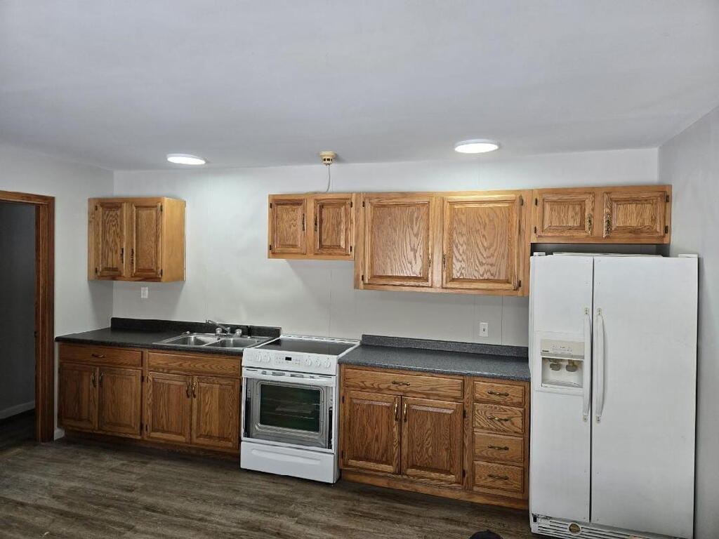 Kitchen with oak cabinets, dark countertops, and white appliances.