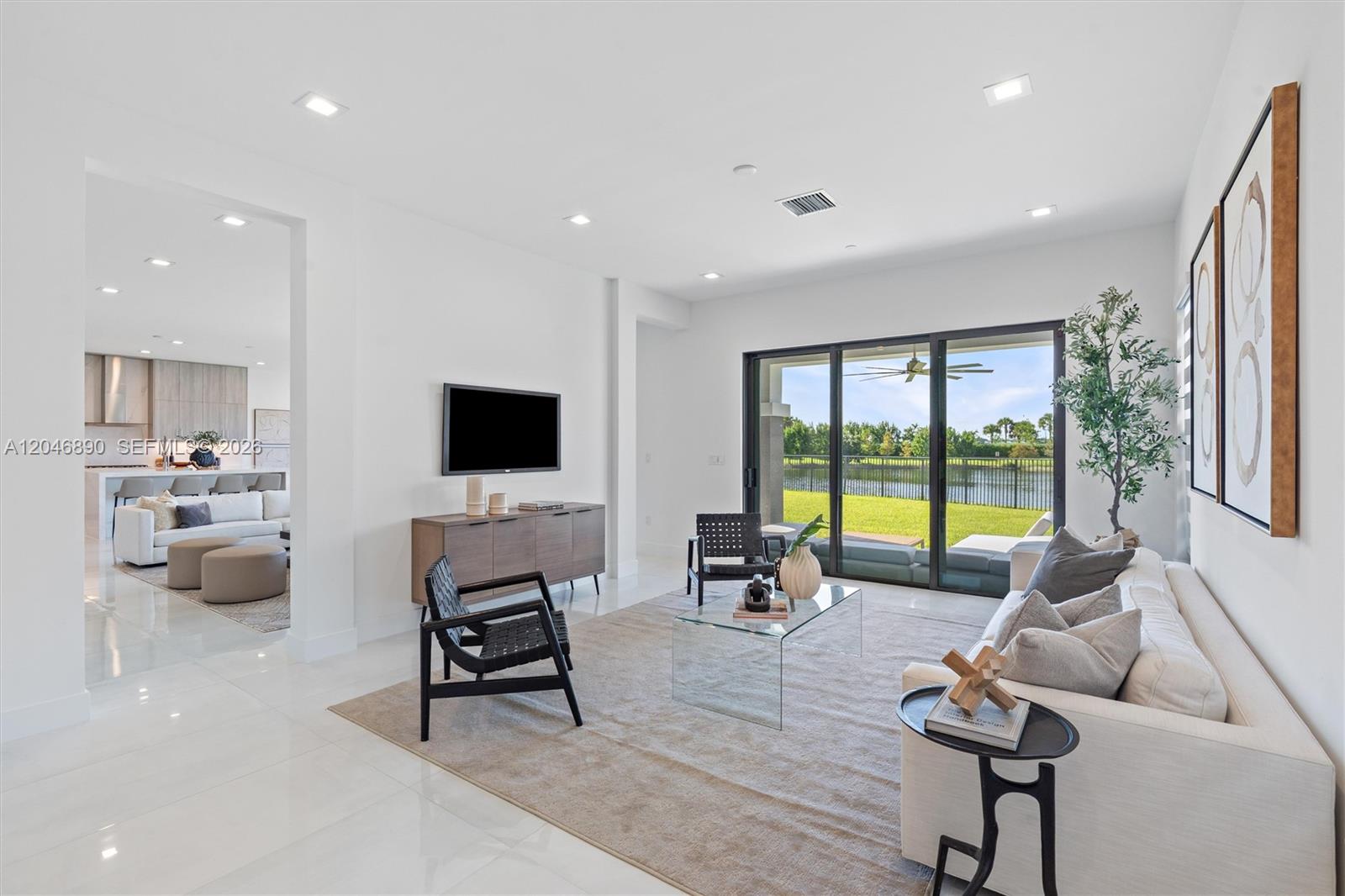 Furnished living room with sliding glass doors overlooking a lawn and lake.