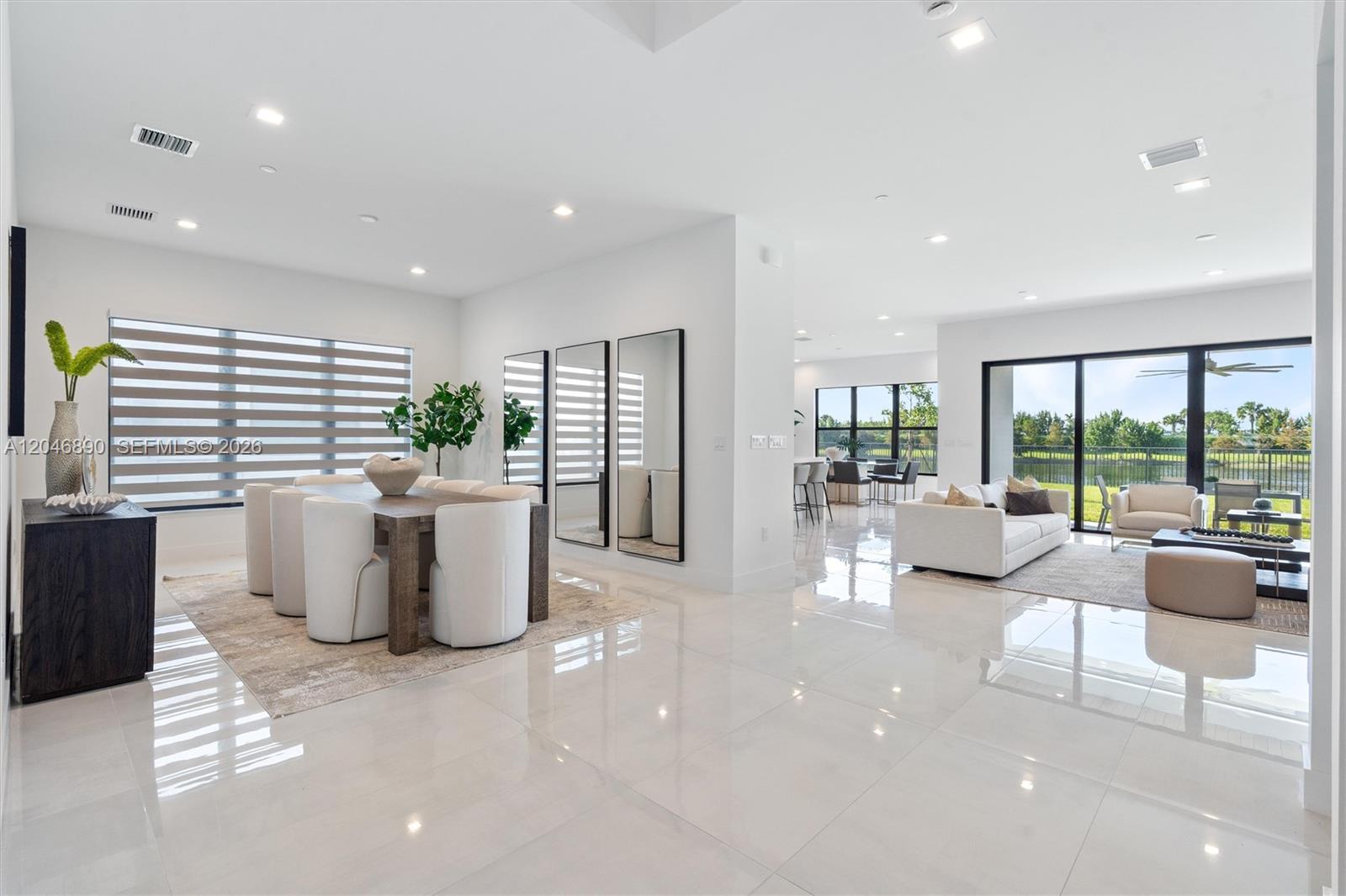 Open-plan dining and living room with glossy tile floors and sliding glass doors overlooking a green lawn.