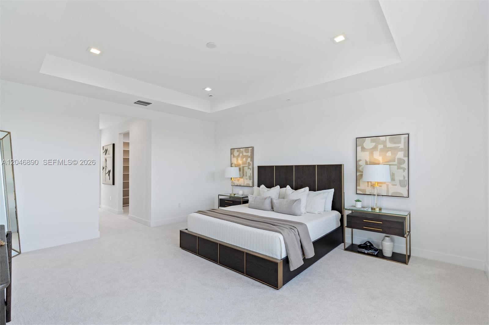Furnished bedroom with a dark wood bed, matching nightstands, and a recessed tray ceiling.