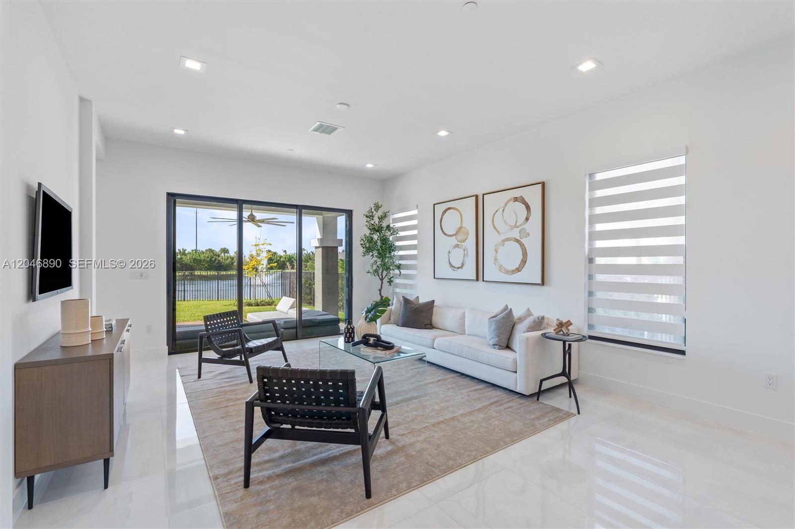 Furnished living room with sliding glass doors overlooking a lake and grassy yard.
