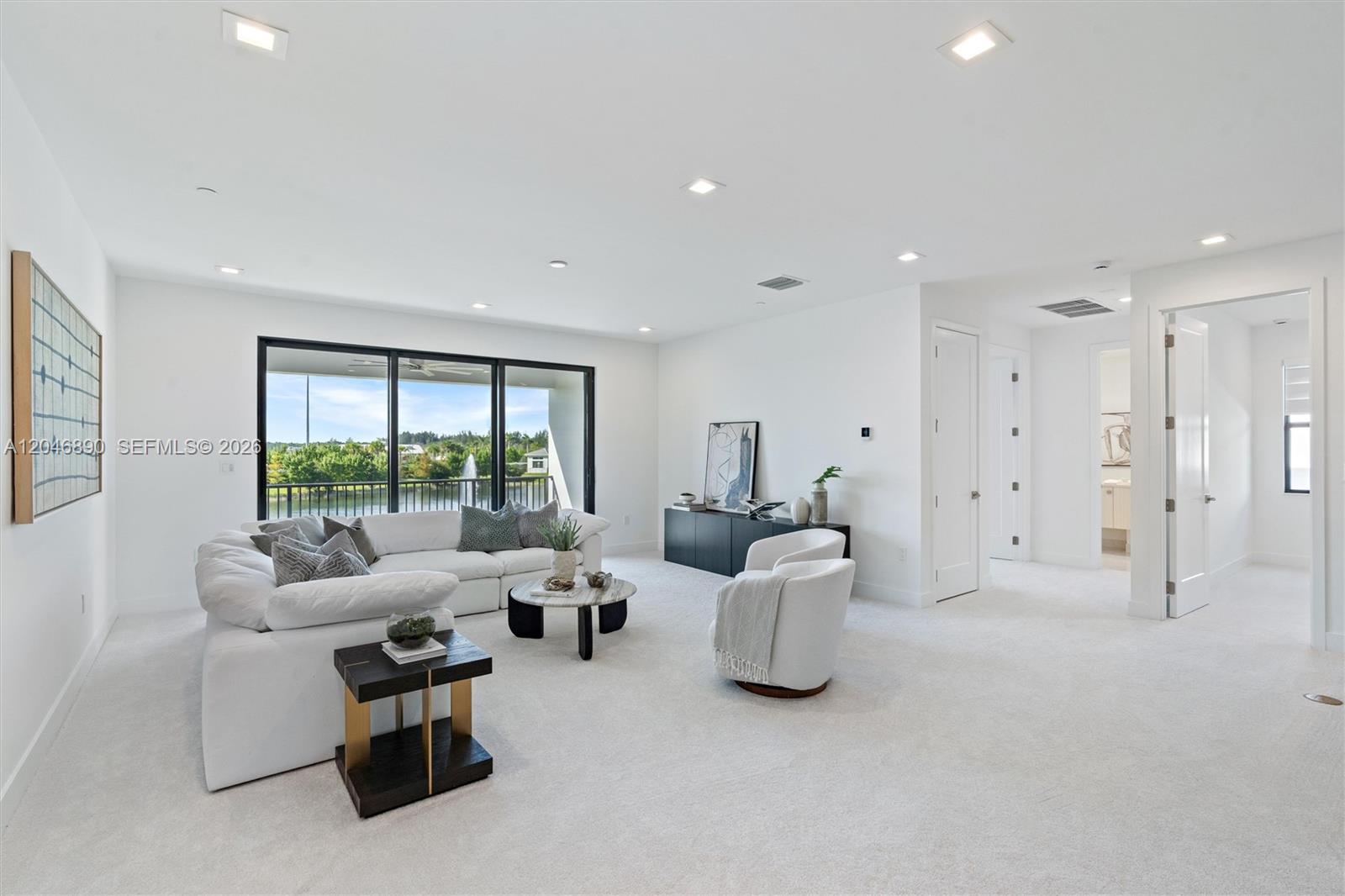 Furnished living room with a white sectional and sliding doors overlooking water and a fountain.