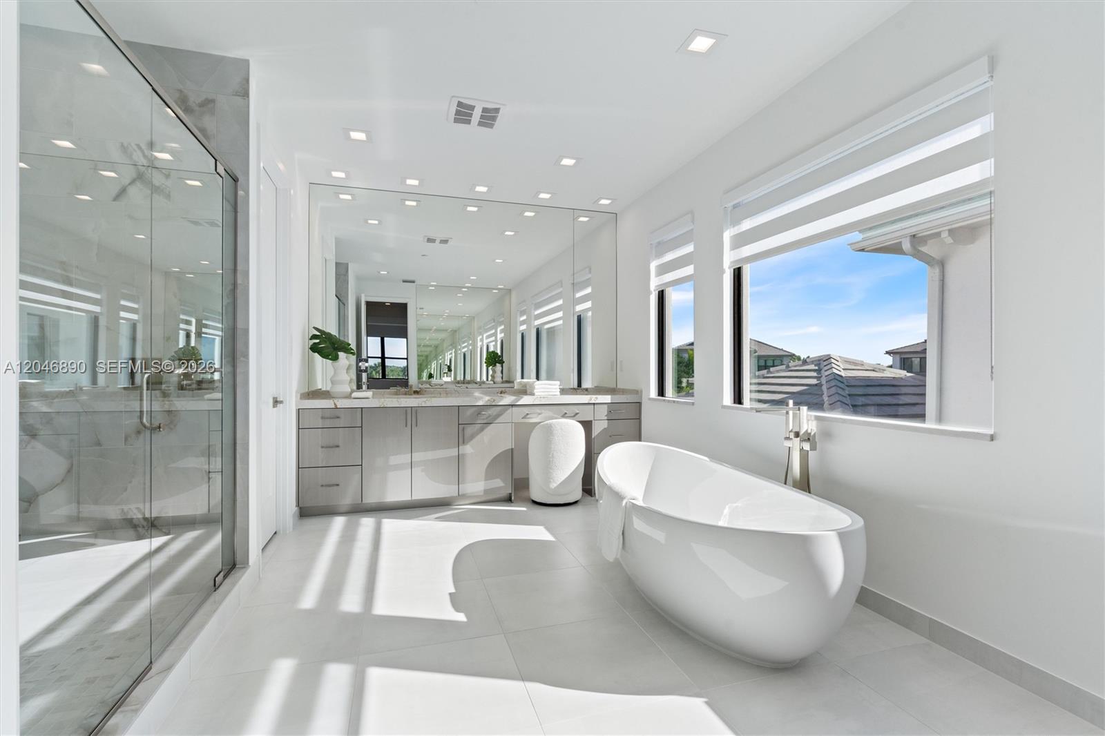 Modern bathroom with a freestanding soaking tub, glass shower, and long mirrored vanity.