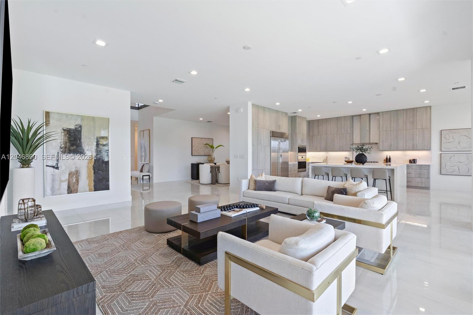 Open-plan living room and kitchen with white sofas, pale gray cabinetry, and a large island.